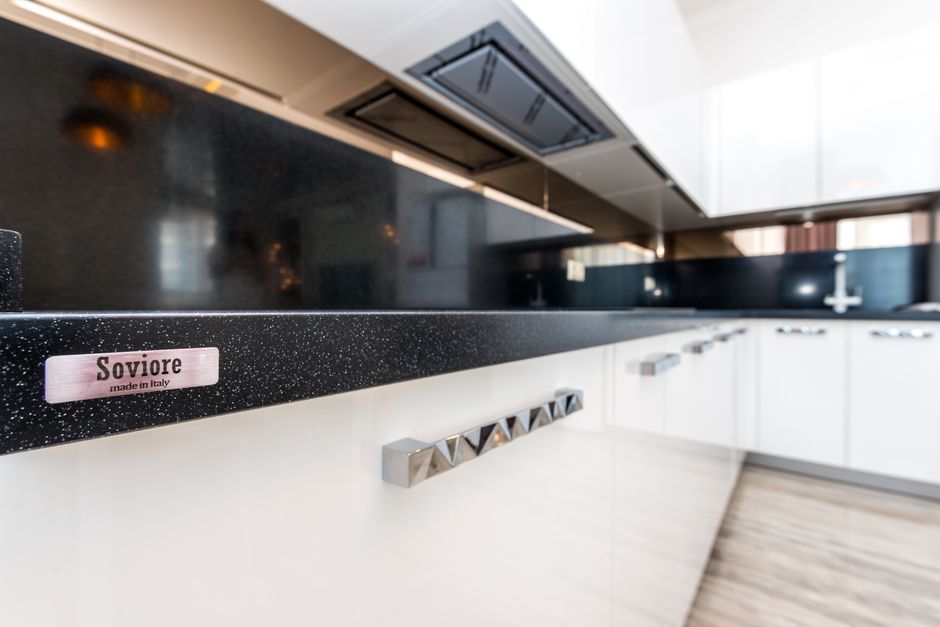Modern kitchen with light cabinets and a stone countertop.